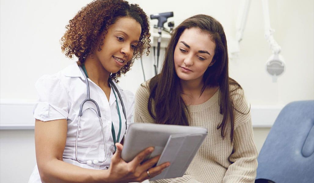 A healthcare professional and a patient discuss information on a tablet.