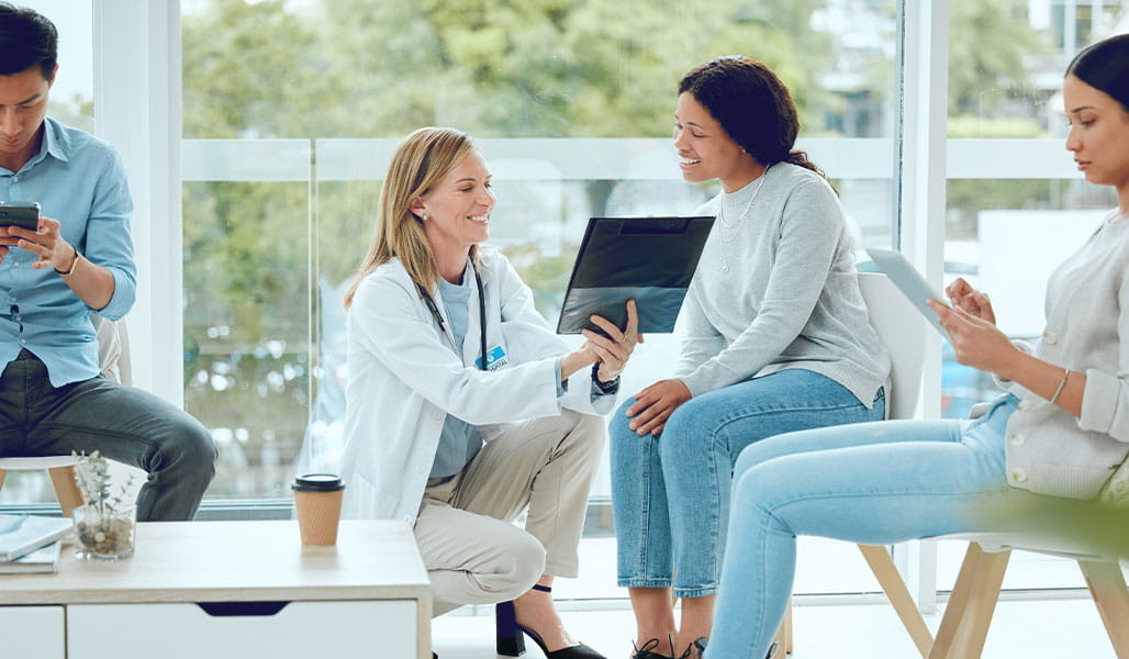 A medical professional consults with clinical trial participants in a waiting room.