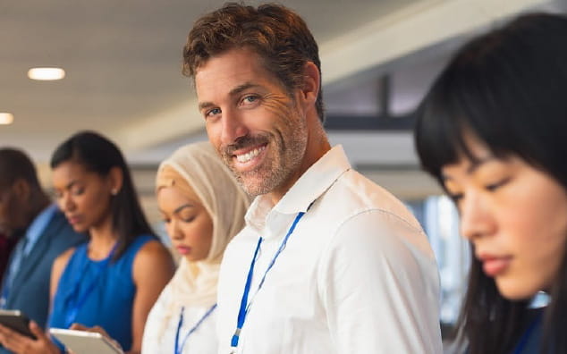 A group of people from different ethnic background standing, watching tabs and phones