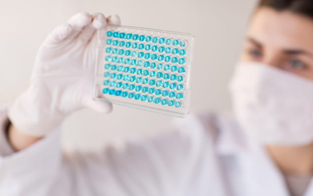 Woman in lab coat holding up test tube in research facility.