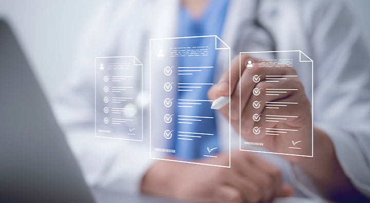 A healthcare professional reviews digital documents with checklists while working on a laptop.