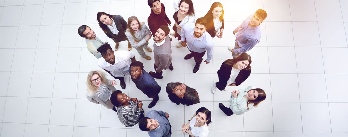 Group of diverse individuals standing together looking up at the camera.