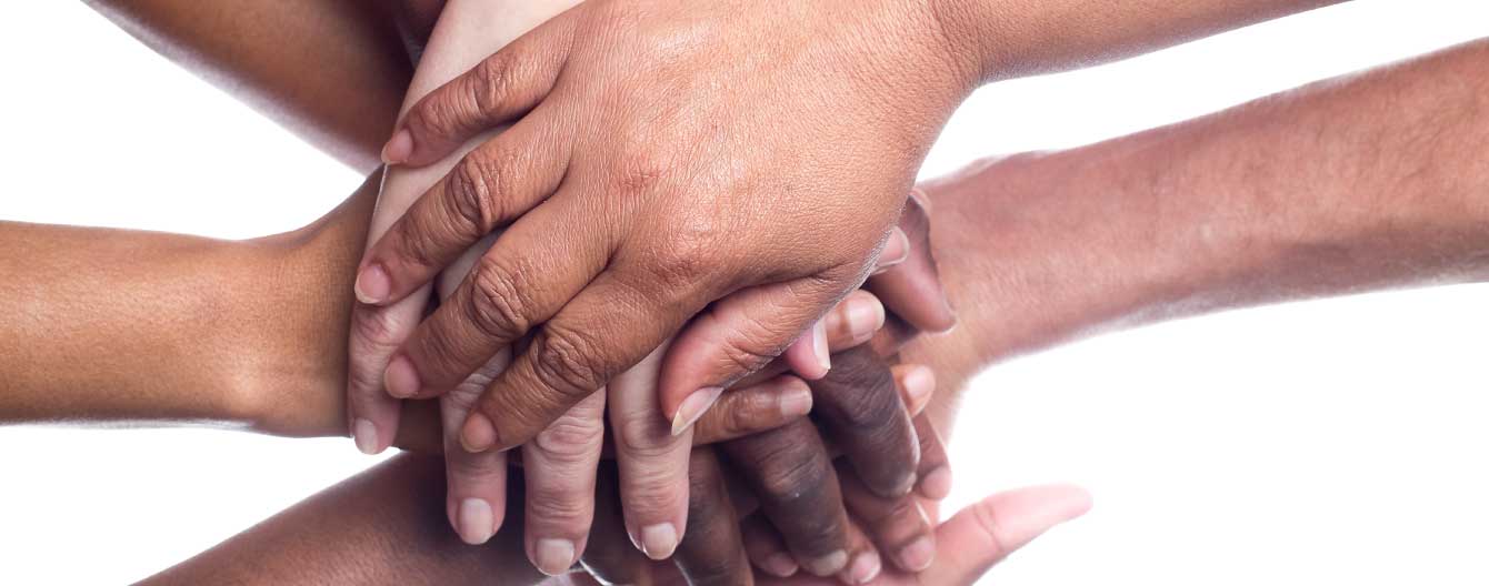 Hands of different ethnicities stacked on top of each other.