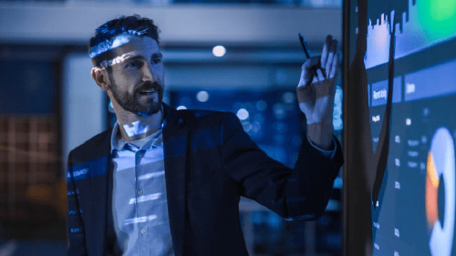 Person presenting data and insights on a digital projector.