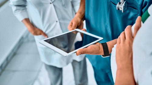 Healthcare professionals collaborating around a tablet device.